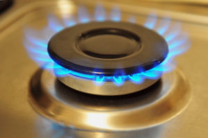 Stainless steel gas burner turned on with blue gas flame.