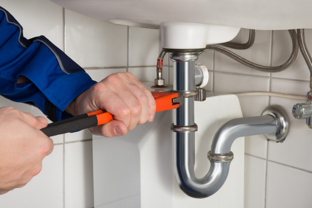 close up of plumber fixing a sink pipe