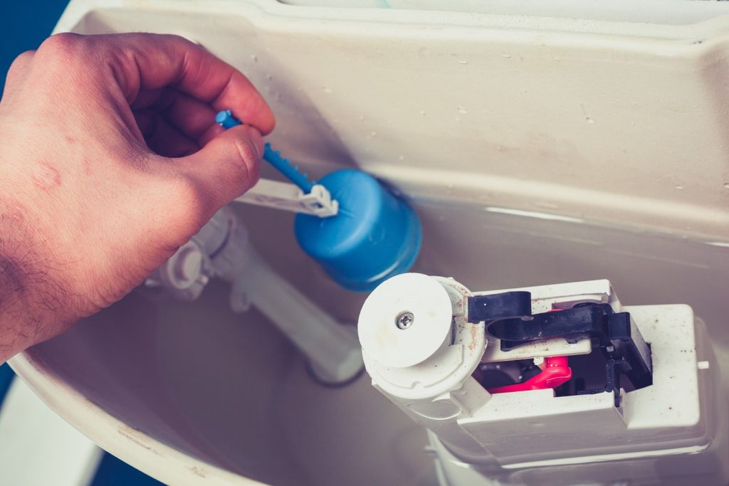 Hand is fixing a toilet cistern at home