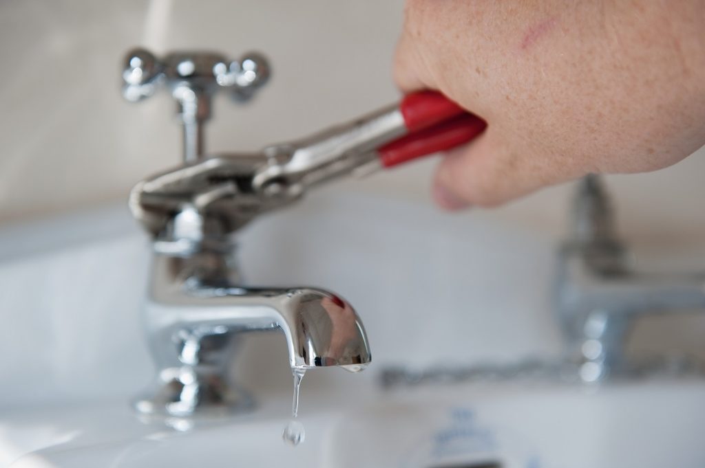 hand holding wrench fixing a leaky faucet