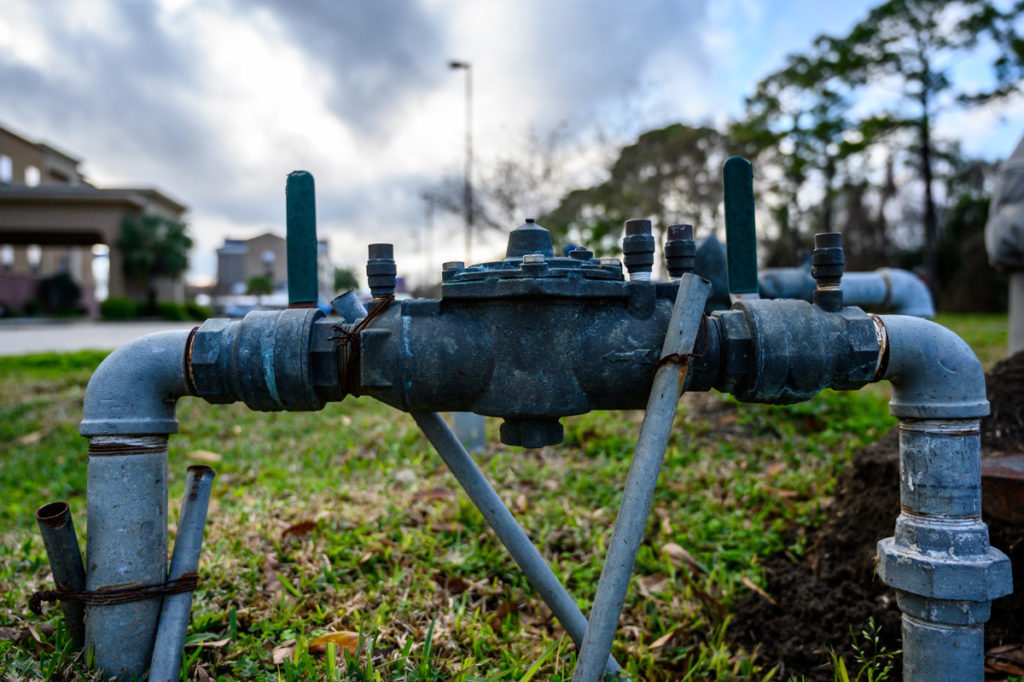 A grey backflow prevention device outside of an El Paso home.