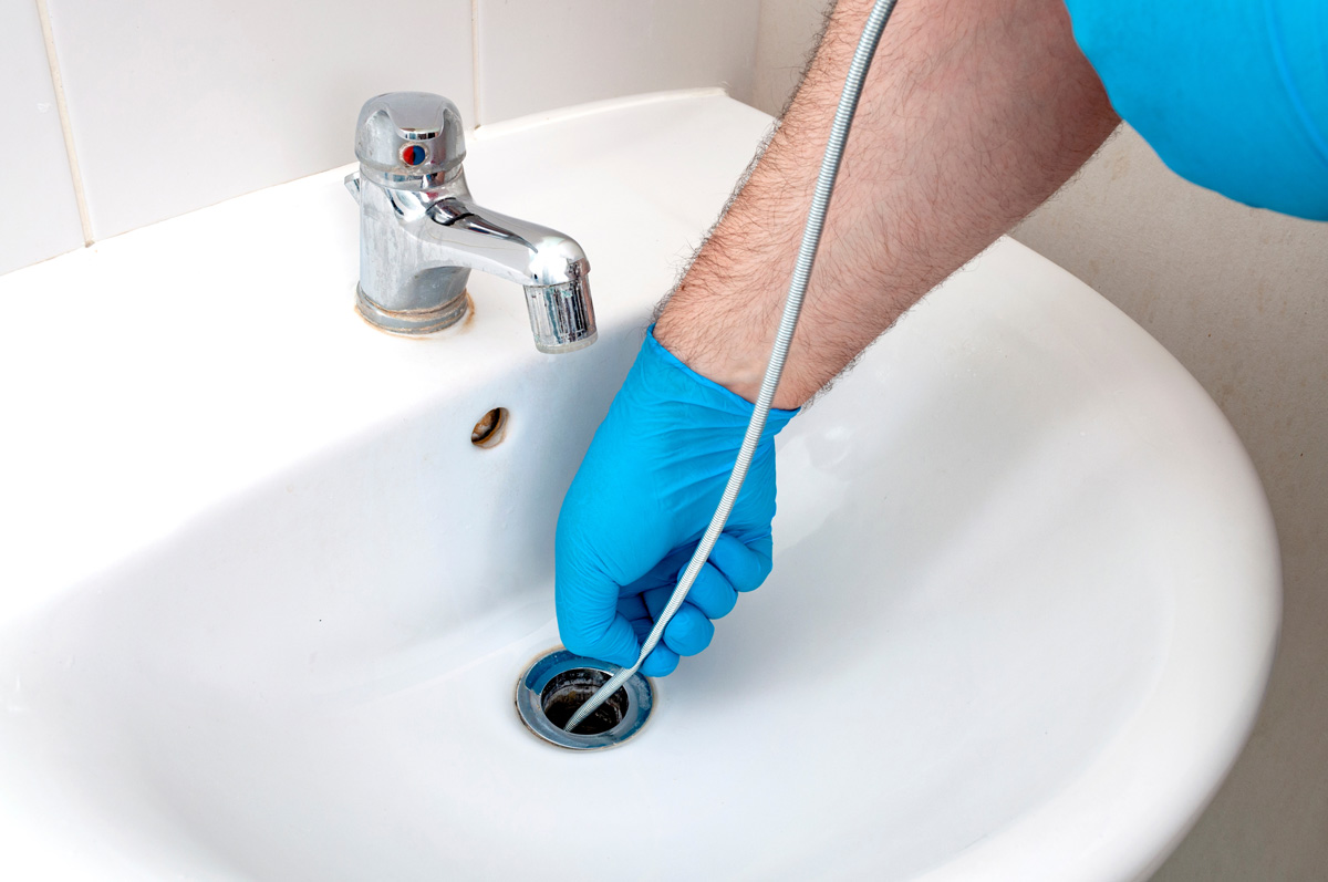 A professional unclogs a sink drain in El Paso.