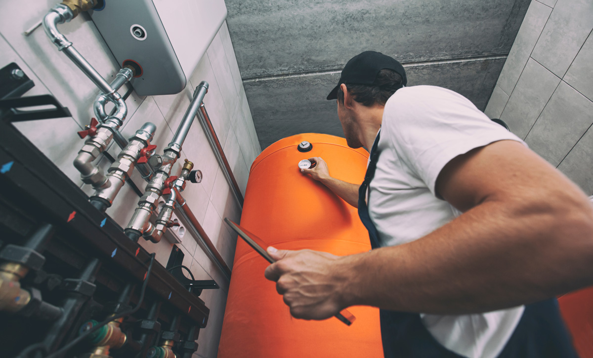 A professional performing a water heater repair on an orange water heater in El Paso.