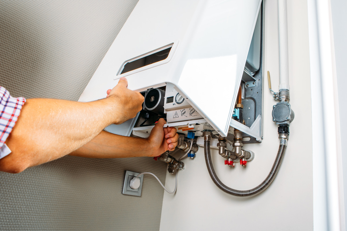 A person performing repairs on a white water heater in an El Paso home.